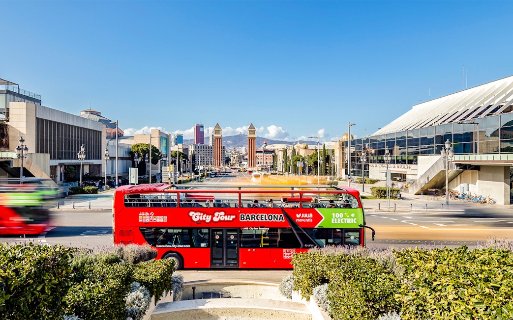 Red double-decker bus on Barcelona hop-on hop-off tour near Plaça d'Espanya.