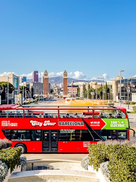 Red double-decker bus on Barcelona hop-on hop-off tour near Plaça d'Espanya.