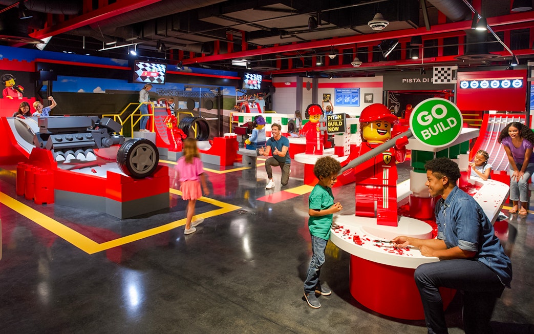 Children and adults building LEGO Ferrari models at Legoland Florida's Build and Race attraction.