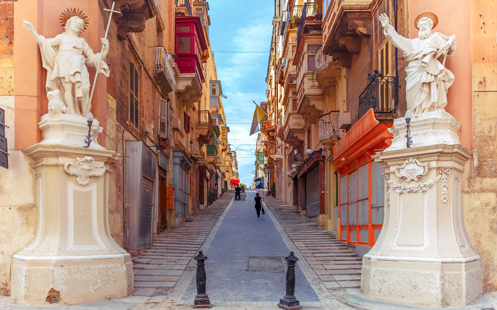 Street view in Valletta with statues and historic buildings.