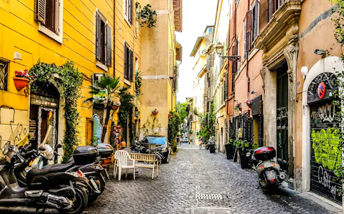 Trastevere street with scooters and colorful buildings, Rome food tour location.