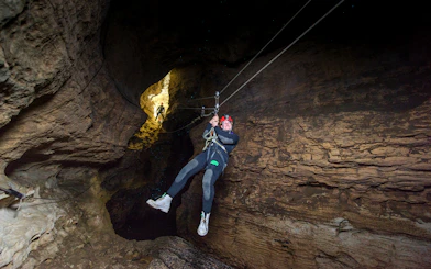 Person ziplining through a cave during a Black Water Rafting experience in Waitomo.