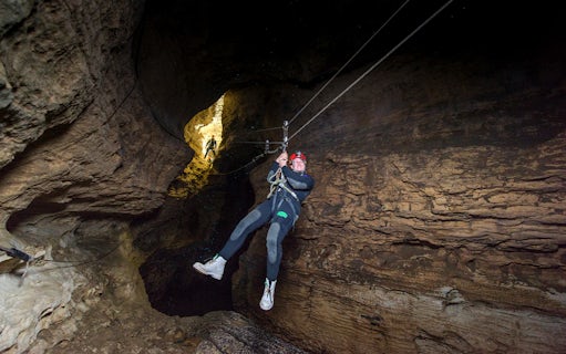 Person ziplining through a cave during a Black Water Rafting experience in Waitomo.