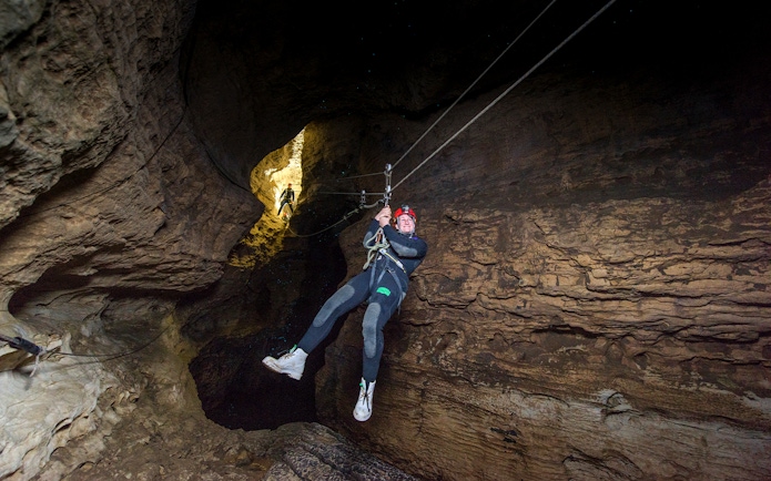 Person ziplining through a cave during a Black Water Rafting experience in Waitomo.