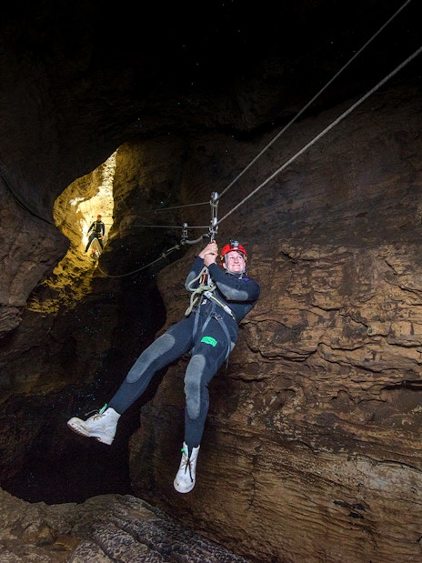 Person ziplining through a cave during a Black Water Rafting experience in Waitomo.