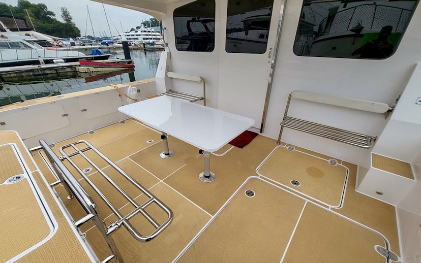 Private yacht SunRise deck with seating and table at marina.