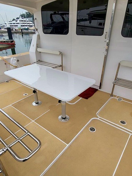 Private yacht SunRise deck with seating and table at marina.
