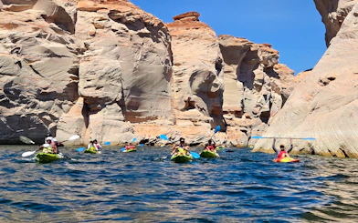 Kayakers paddling near sandstone cliffs on Antelope Canyon tour, Page.