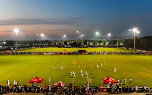 Rugby match at sunset during Emirate's Dubai 7's tournament.