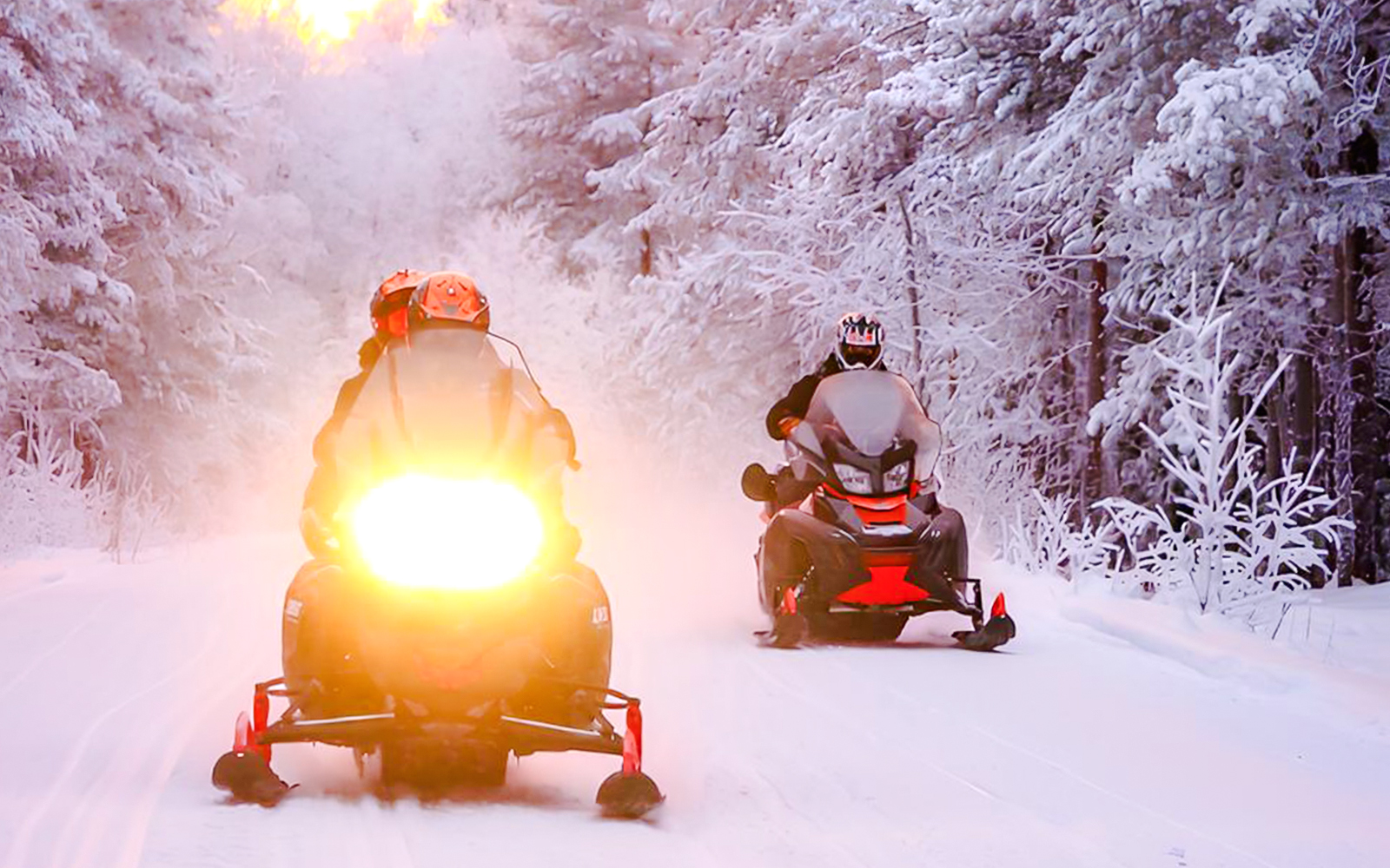 Snowmobilers riding through snowy forest during 1-Hour Snowmobile Safari Adventure from Rovaniemi.