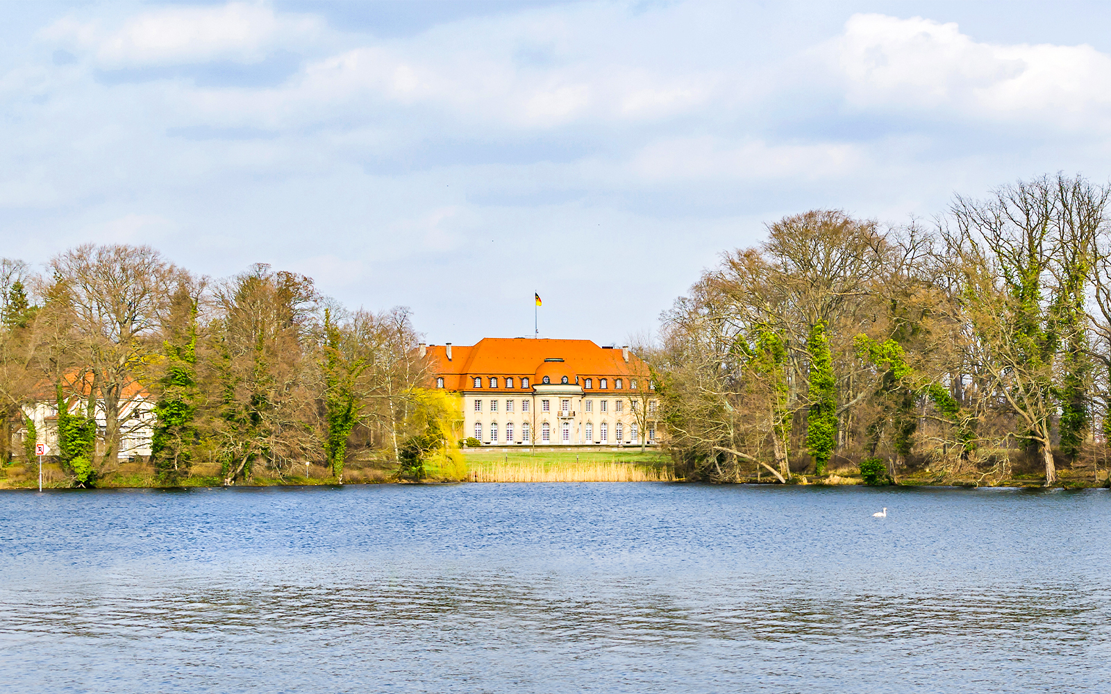 Borsig Villa by Lake Tegel, Berlin, surrounded by trees and water.