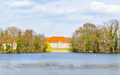 Borsig Villa by Lake Tegel, Berlin, surrounded by trees and water.