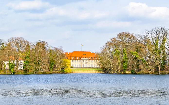 Borsig Villa by Lake Tegel, Berlin, surrounded by trees and water.