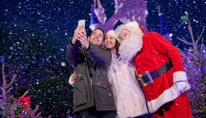 Santa Claus meeting visitors at a Christmas event in a festive setting.