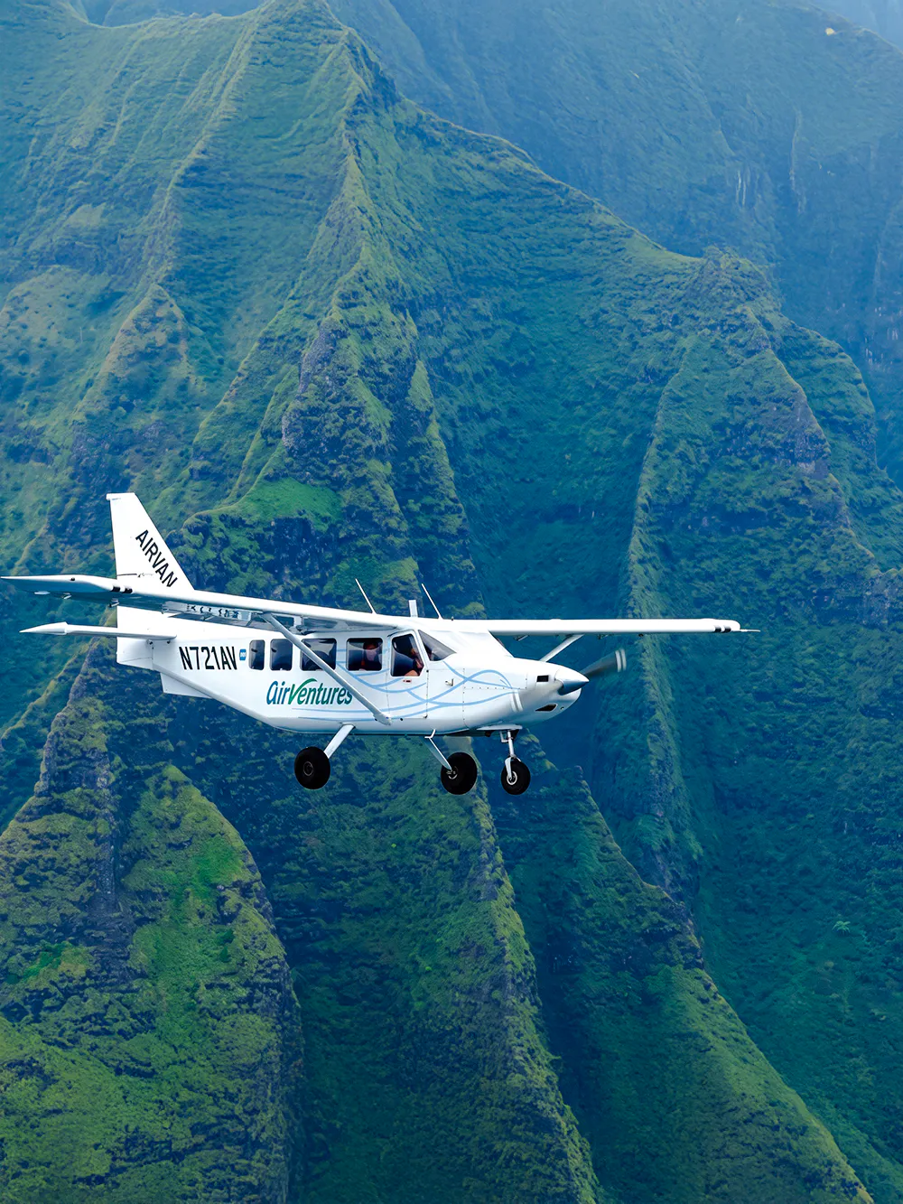 Airplane flying over lush green mountains on a Kauai air tour.