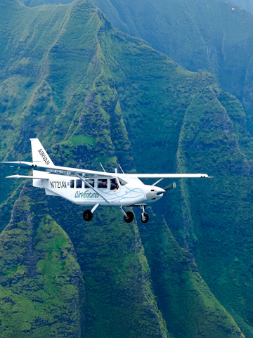 Airplane flying over lush green mountains on a Kauai air tour.