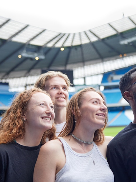 Participants taking a selfie on the field of Manchester City Stadium.