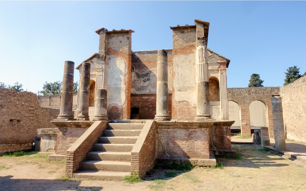Ancient ruins of a temple in Pompeii with stone columns and steps.