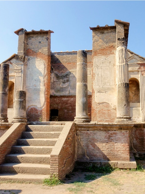 Ancient ruins of a temple in Pompeii with stone columns and steps.