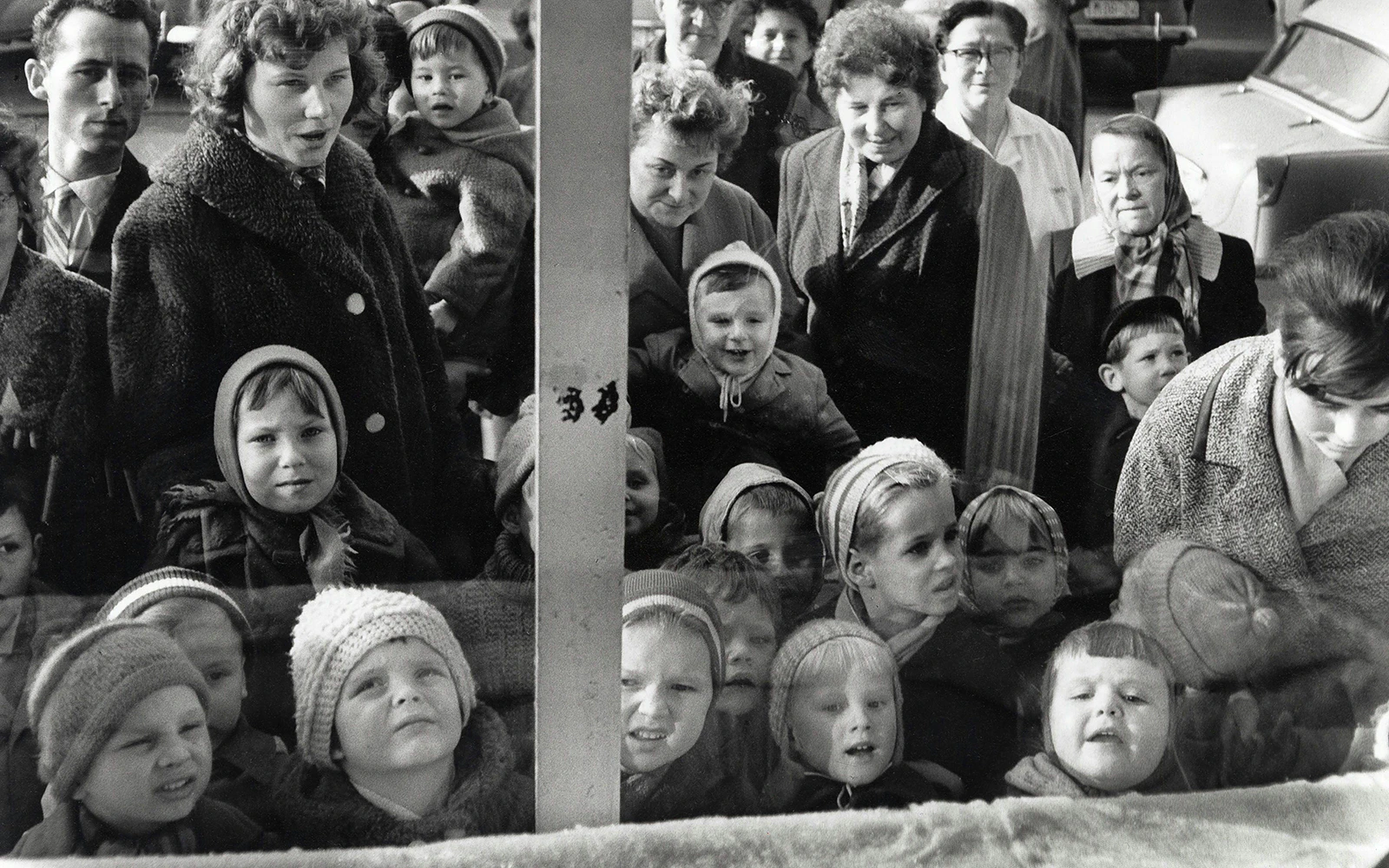 Children and adults looking through a window at Thomas Billhardt exhibit, Fotografiska Berlin.