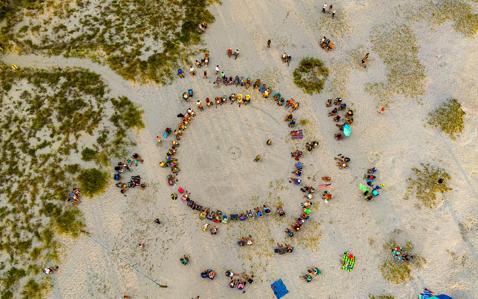 Aerial view of a group of people standing in a circle at a beach
