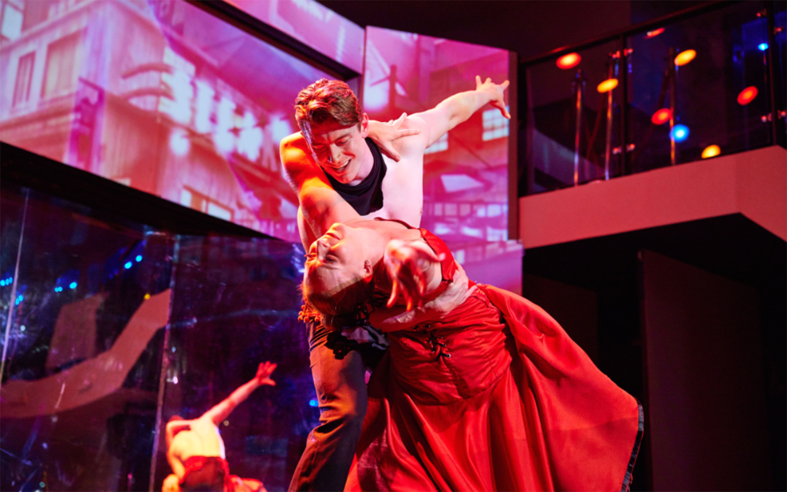 Dancers performing on a cabaret cruise with vibrant lighting and elegant costumes.