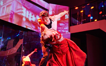 Dancers performing on a cabaret cruise with vibrant lighting and elegant costumes.