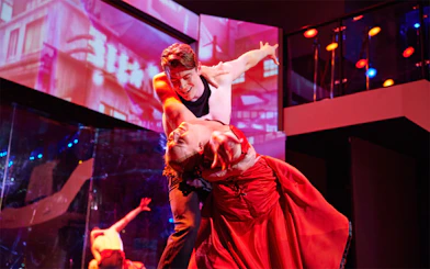 Dancers performing on a cabaret cruise with vibrant lighting and elegant costumes.