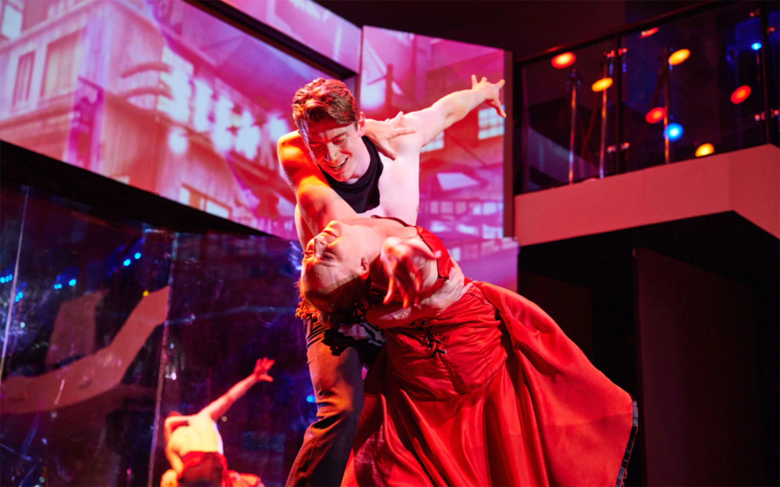Dancers performing on a cabaret cruise with vibrant lighting and elegant costumes.