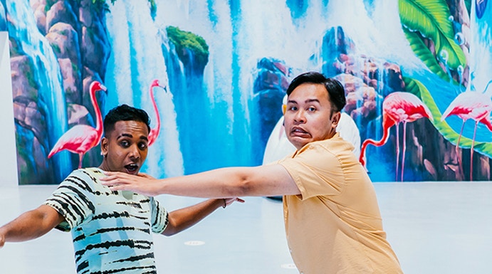 Visitors interacting with 3D art at Trick Eye Museum, featuring dolphins and waterfalls.
