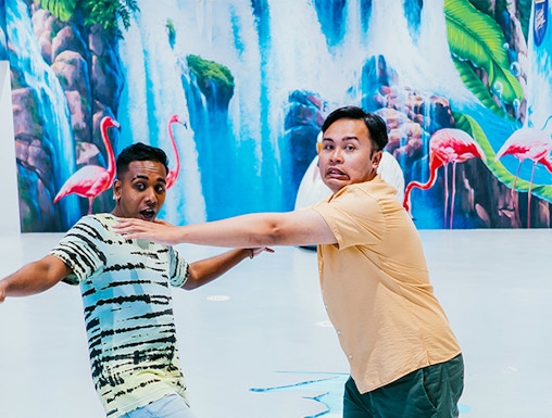 Visitors interacting with 3D art at Trick Eye Museum, featuring dolphins and waterfalls.