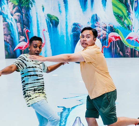 Visitors interacting with 3D art at Trick Eye Museum, featuring dolphins and waterfalls.