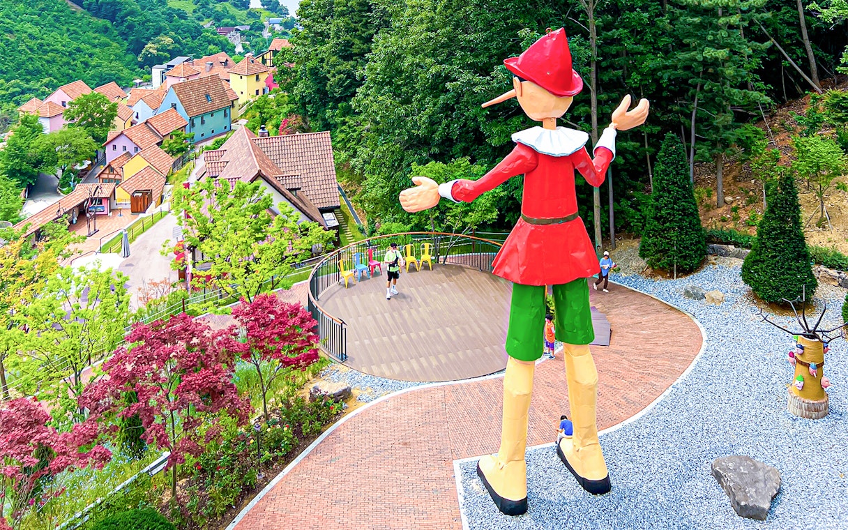 Large Pinocchio statue overlooking colorful houses in Italian Village, South Korea.