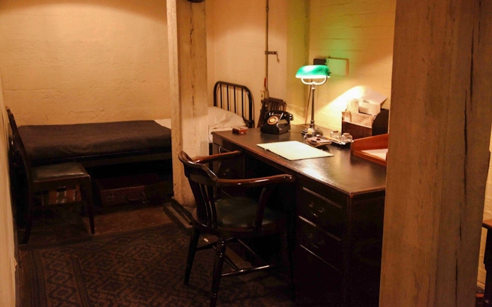 Desk and bed in Churchill War Rooms, London, featuring vintage phone and lamp.