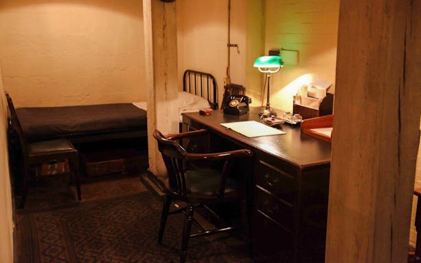 Desk and bed in Churchill War Rooms, London, featuring vintage phone and lamp.