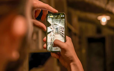 Person photographing historical pharmacy cellar shelves on a smartphone.