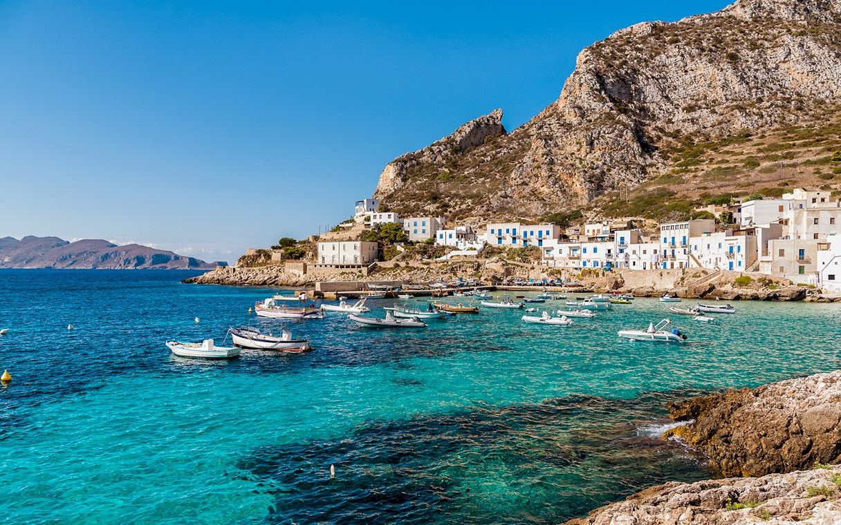 Boats anchored near the rocky coastline of Egadi Islands, viewed from Marsala.