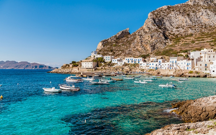 Boats anchored near the rocky coastline of Egadi Islands, viewed from Marsala.