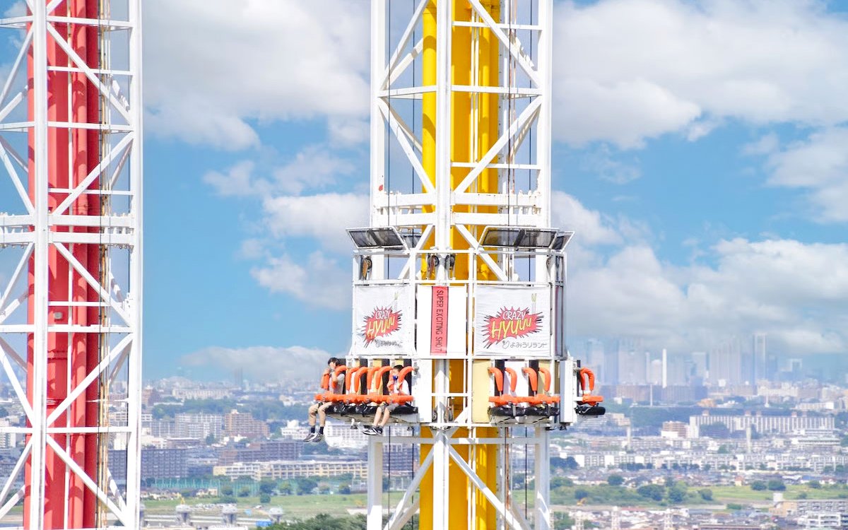 Crazy Hyuuu! drop tower ride at Yomiuriland amusement park, Tokyo, with city skyline in background.