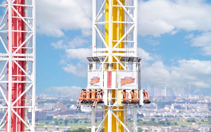 Crazy Hyuuu! drop tower ride at Yomiuriland amusement park, Tokyo, with city skyline in background.