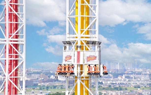 Crazy Hyuuu! drop tower ride at Yomiuriland amusement park, Tokyo, with city skyline in background.