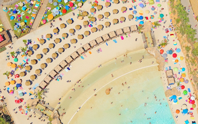 Aerial view of Zoomarine Algarve beach with sunbathers, umbrellas, and clear water.