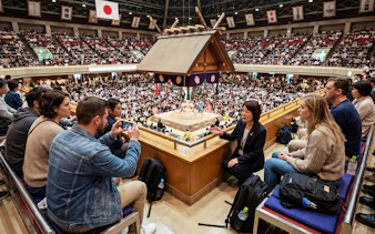 Guided tour group at Ryogoku Kokugikan watching sumo match in Tokyo, Japan.