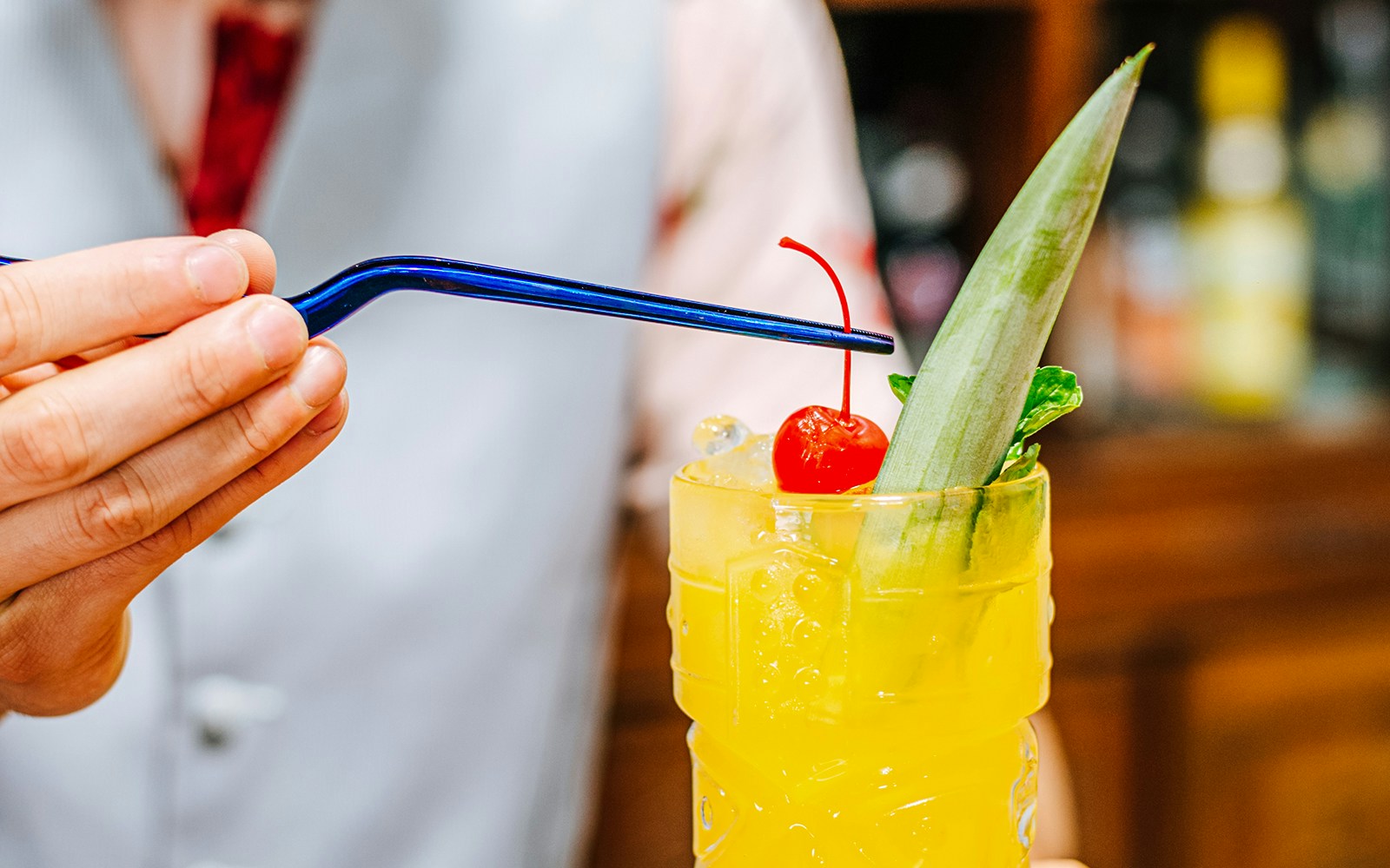 Bartender garnishing tiki cocktail with a cherry.