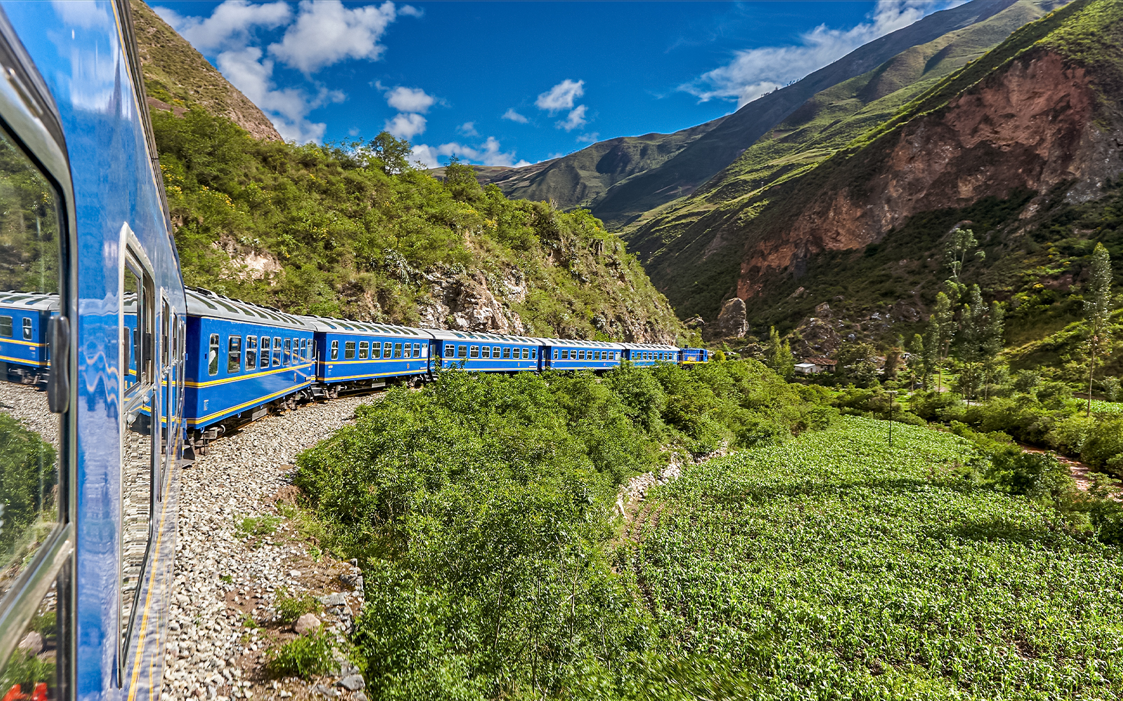 Train traveling through lush mountains near Cusco, Peru.