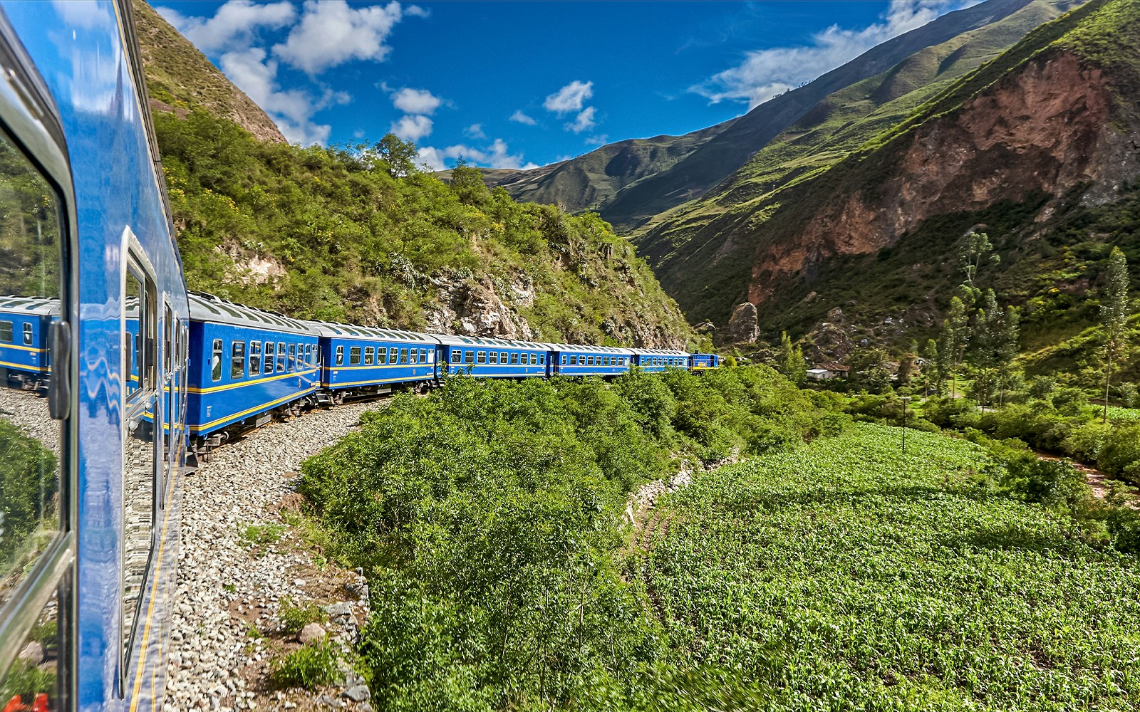 Train traveling through lush mountains near Cusco, Peru.