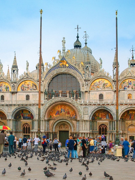St. Mark's Basilica facade with tourists and pigeons in Venice, Italy.