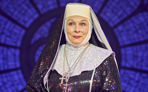 Nun in sparkling habit on stage during Sister Act performance.