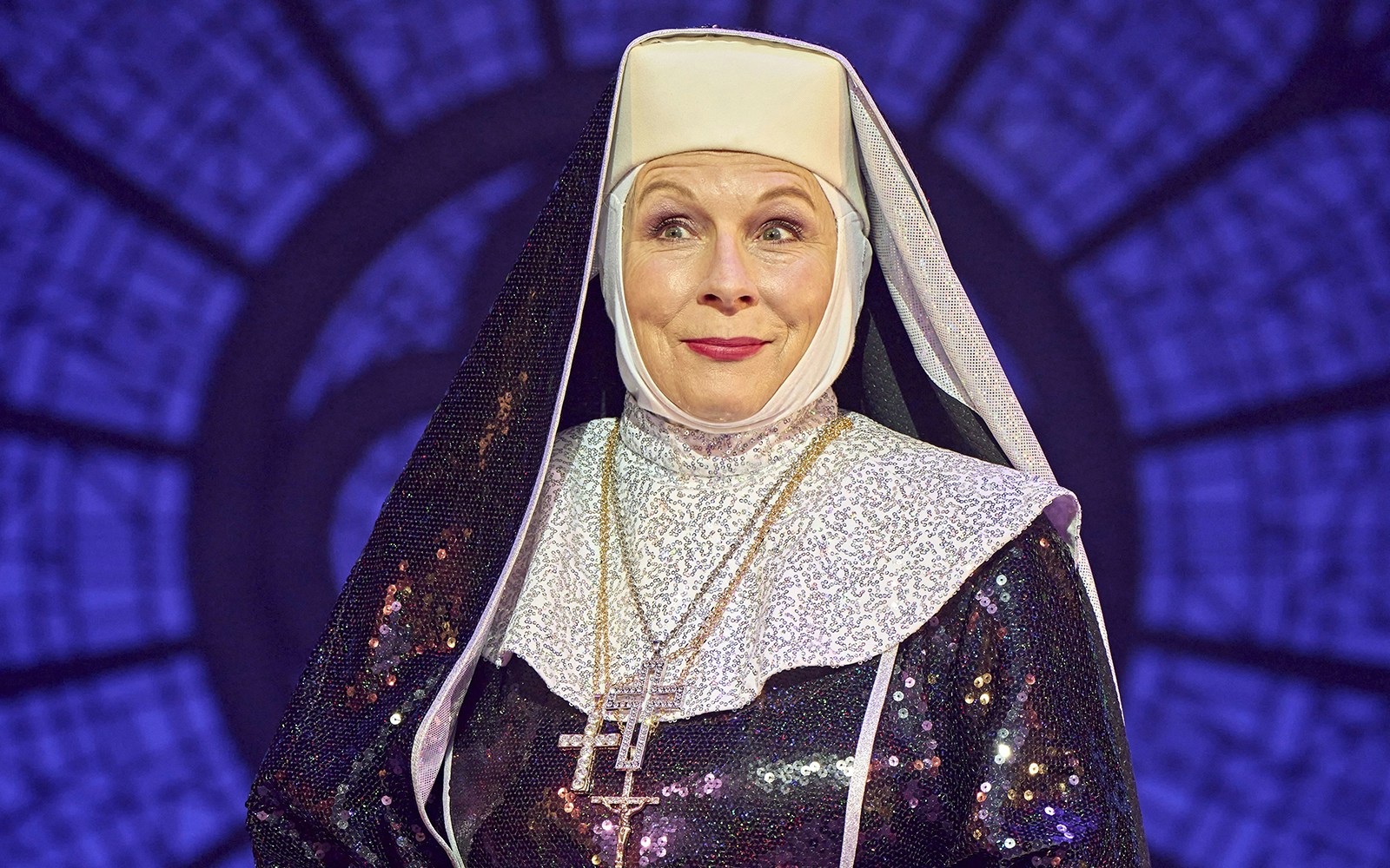 Nun in sparkling habit on stage during Sister Act performance.