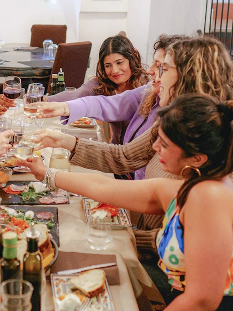 Group toasting with wine during a guided food tour in Trastevere, Rome.